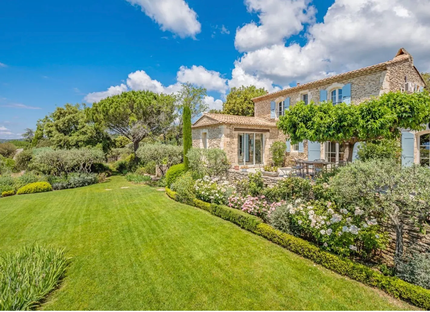 The lawn and flower beds running up to the house and its shaded terrace